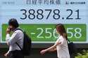 People walk in front of an electronic stock board showing Japan's Nikkei 225 index at a securities …