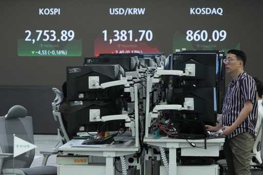 A currency trader watches monitors near the screen showing the Korea Composite Stock Price Index…